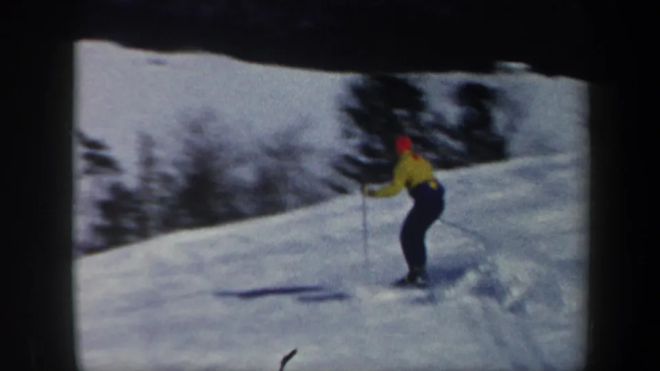 1962 Vermont 8mm frame showing a skier with poles on a snow-covered slope, with dark trees and twilight sky in the background.