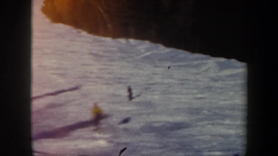 1962 Vermont frame with the skier now small in the distance on the snowy slope, marked by long shadows and soft 8mm focus.
