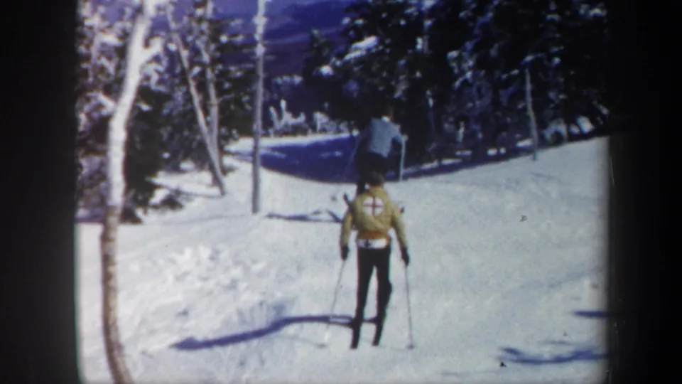 1962 Vermont ski footage showing a skier from behind on a snowy slope, with trees, poles, and a red-cross-style marking visible.