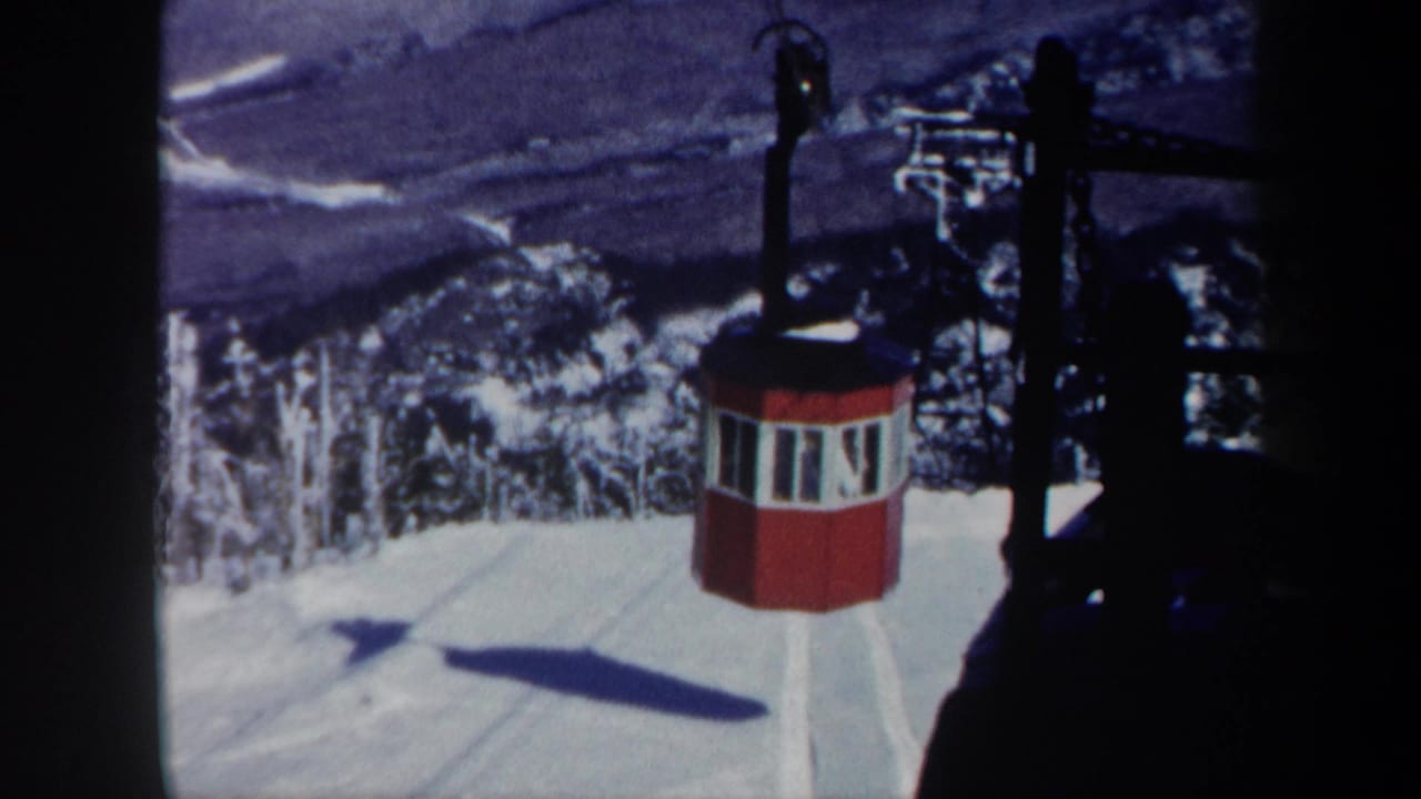 1962 Vermont 8mm frame showing a red octagonal gondola on a snowy mountain cableway above trees and a distant valley.