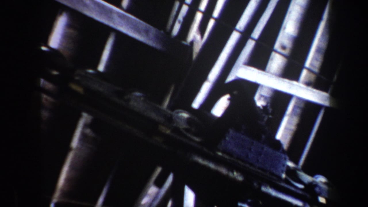 Close view of dark ski lift machinery with metal rails and pulleys crossing the frame.
