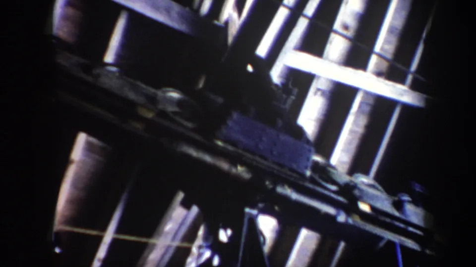 Close 8mm view of Vermont ski lift components, with bright rods, dark housings, and pulley hardware dominating the frame.