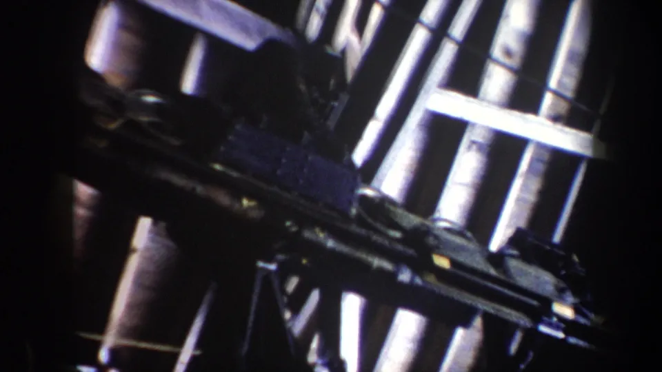 1962 Vermont ski-lift machinery seen at an angle, with rails, wheels, and dark support elements in handheld 8mm footage.