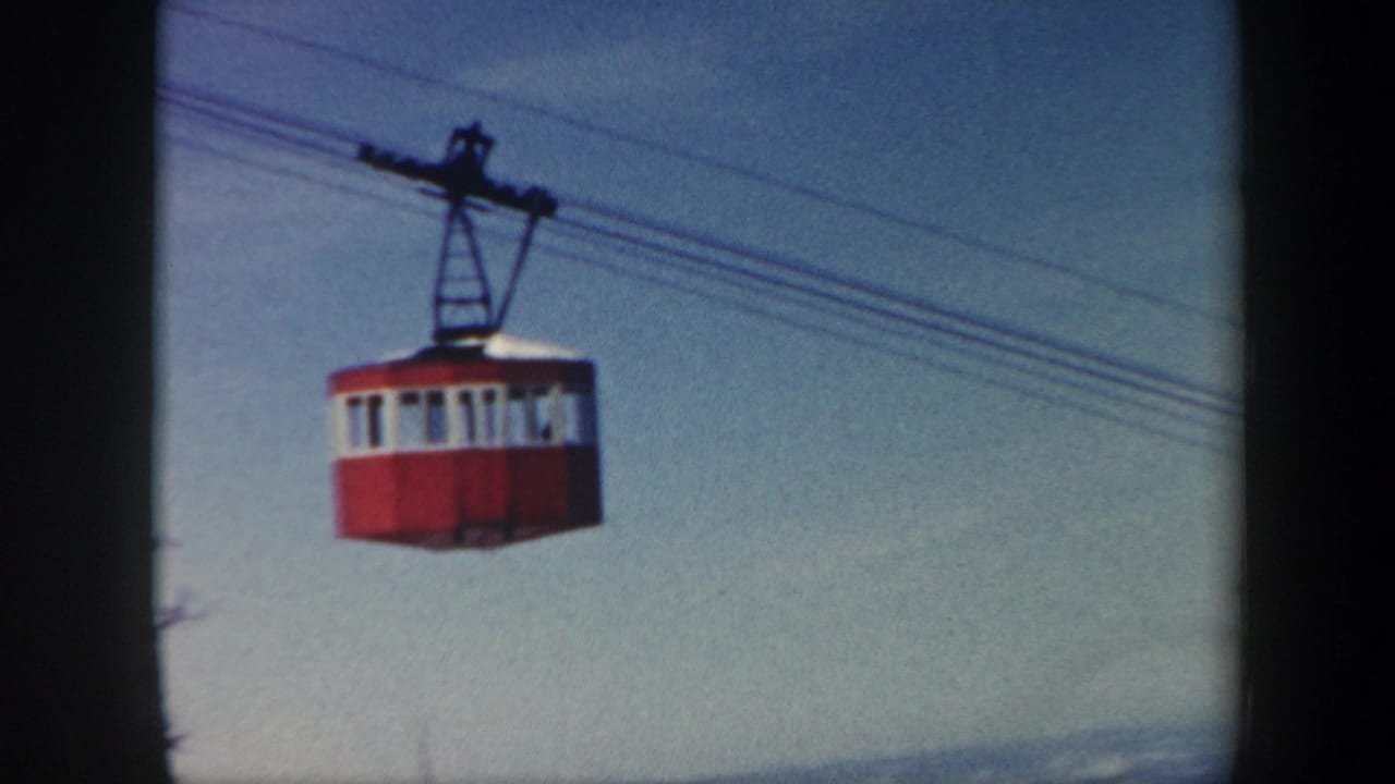 1962 Vermont 8mm frame showing a red and white cable car crossing the sky on overhead cables.