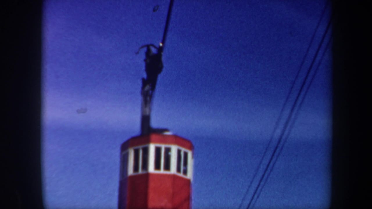 Cable-car cabin top and suspension arm framed low against a blue sky.