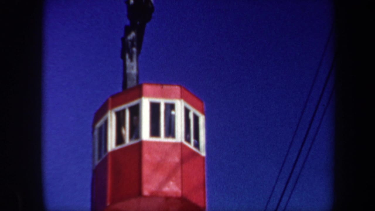 1962 Vermont 8mm frame showing a red cable car cabin below a deep blue sky, with cables and dark film edges visible.