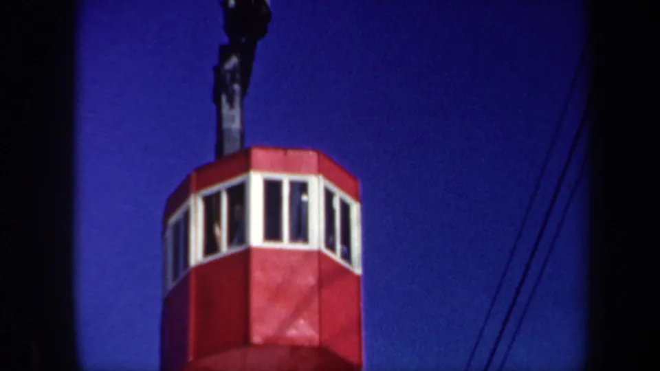 1962 Vermont 8mm frame showing a red cable car cabin below a deep blue sky, with cables and dark film edges visible.