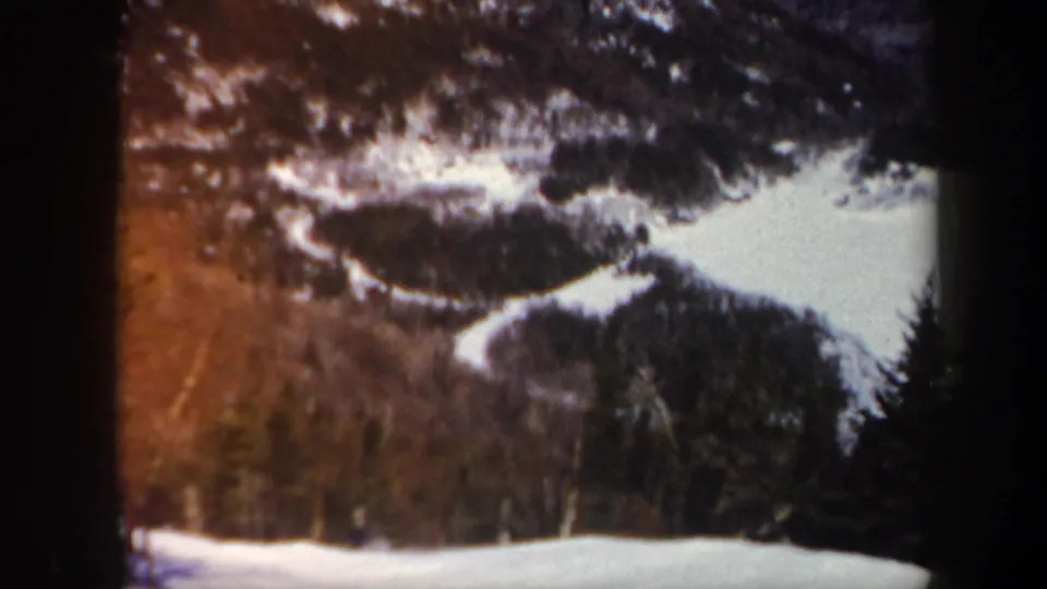 Soft 1962 Vermont home-movie view of snowy mountain trails through forest, with warm color fading and visible film borders.