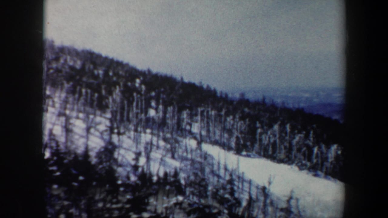 1962 Vermont 8mm frame showing a snowy mountain slope dotted with bare winter trees and distant haze.