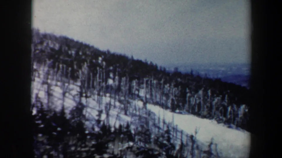 1962 Vermont 8mm frame showing a snowy mountain slope dotted with bare winter trees and distant haze.