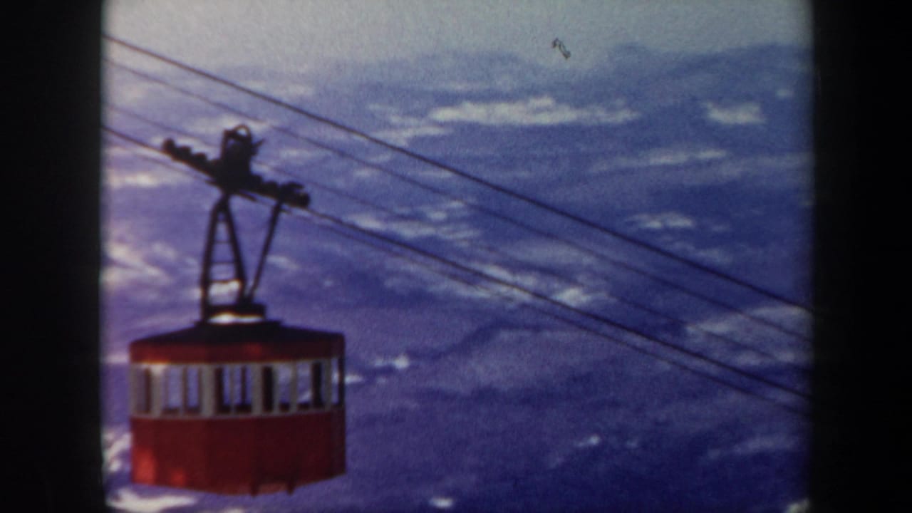 1962 Vermont 8mm frame showing a red gondola cabin suspended on cables over snowy mountain ridges.