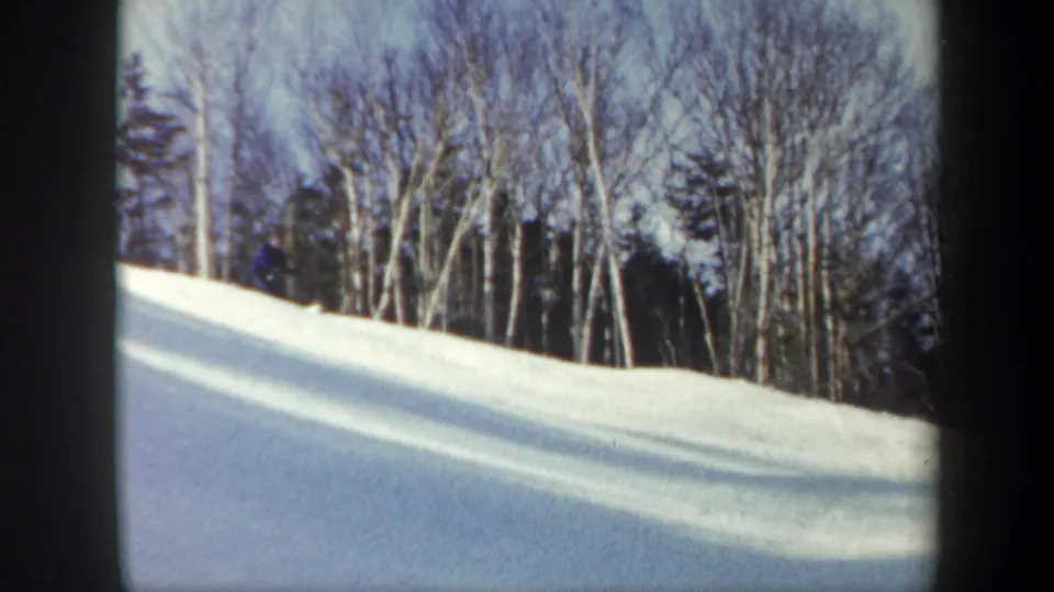Vermont winter slope after the skier has left the frame, showing bright snow, bare deciduous trees, and evergreens under pale sky.