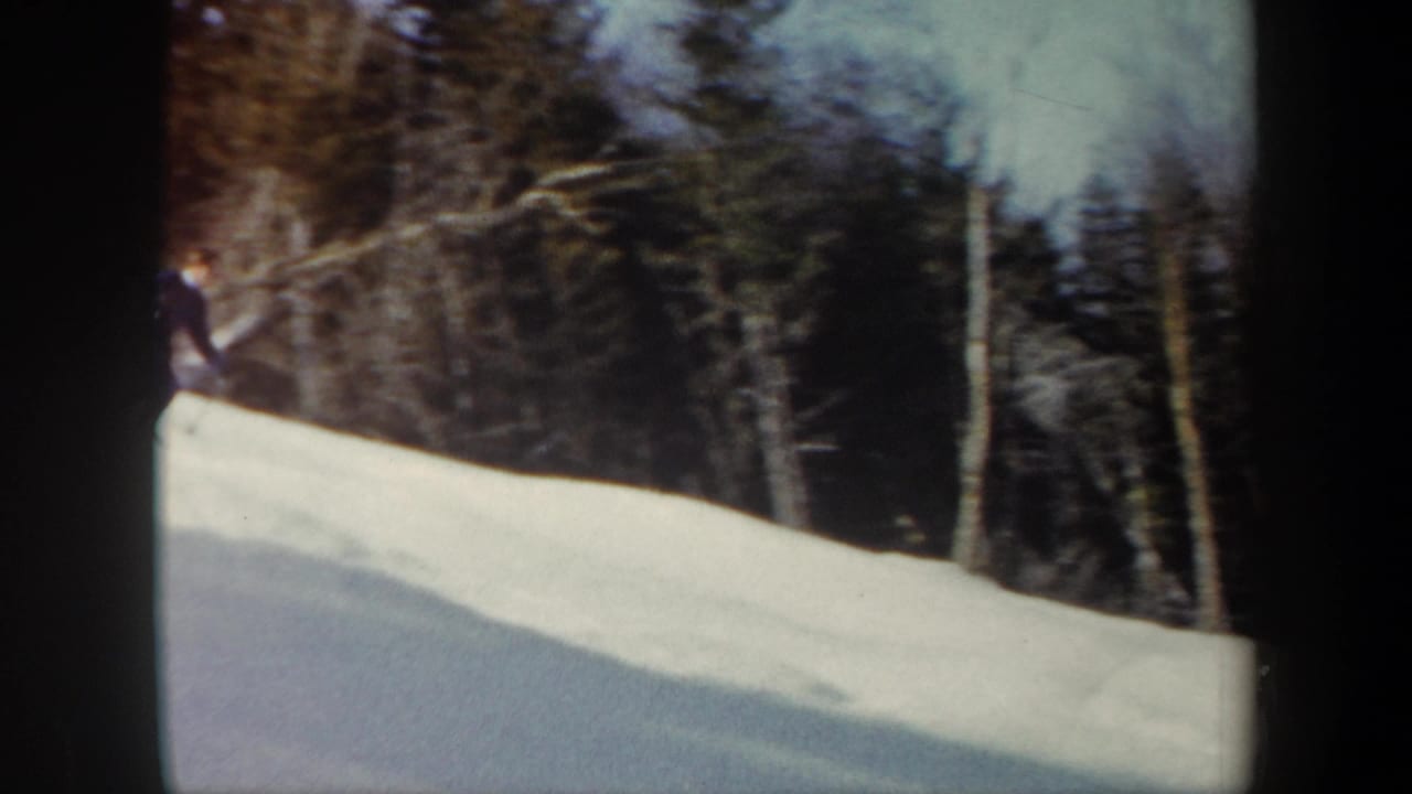 1962 Vermont 8mm frame with a skier partly entering a snowy hillside bordered by bare trees and evergreens.
