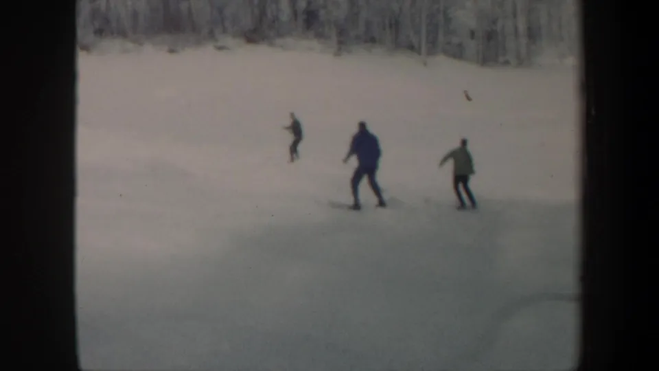 A home-movie frame shows three skiers on a Vermont snow slope, filmed from a distance in 1962.