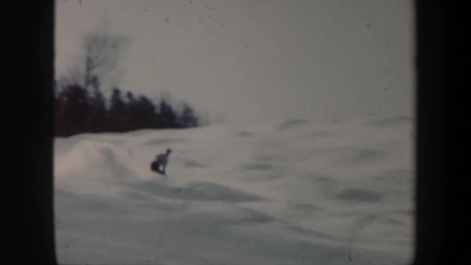 A distant skier moves down an open Vermont ski slope in soft 8mm winter footage from 1962.