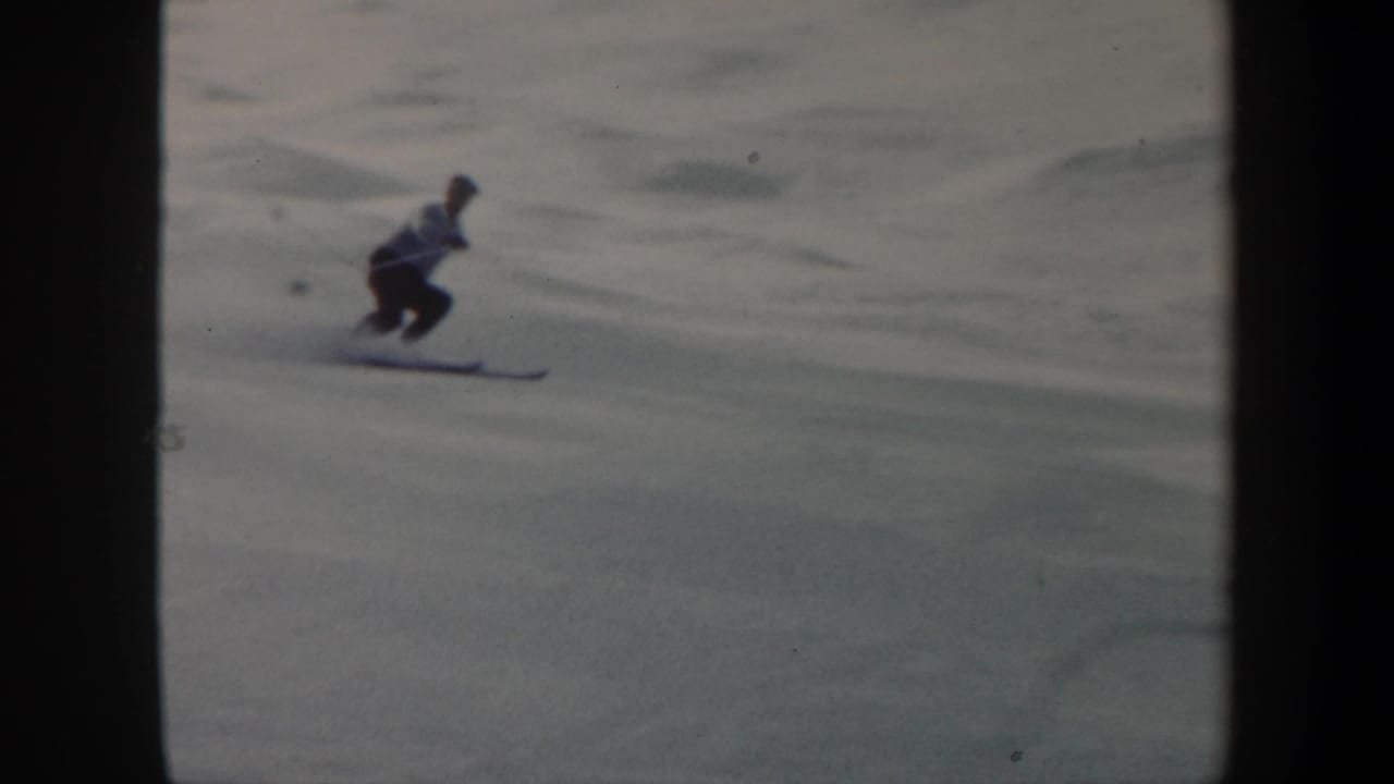 Skier crouches while crossing an open snow-covered slope.