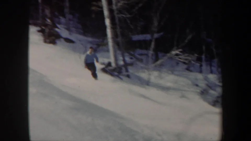The skier continues downhill through a snowy Vermont woodland slope, filmed in soft 1962 8mm color.