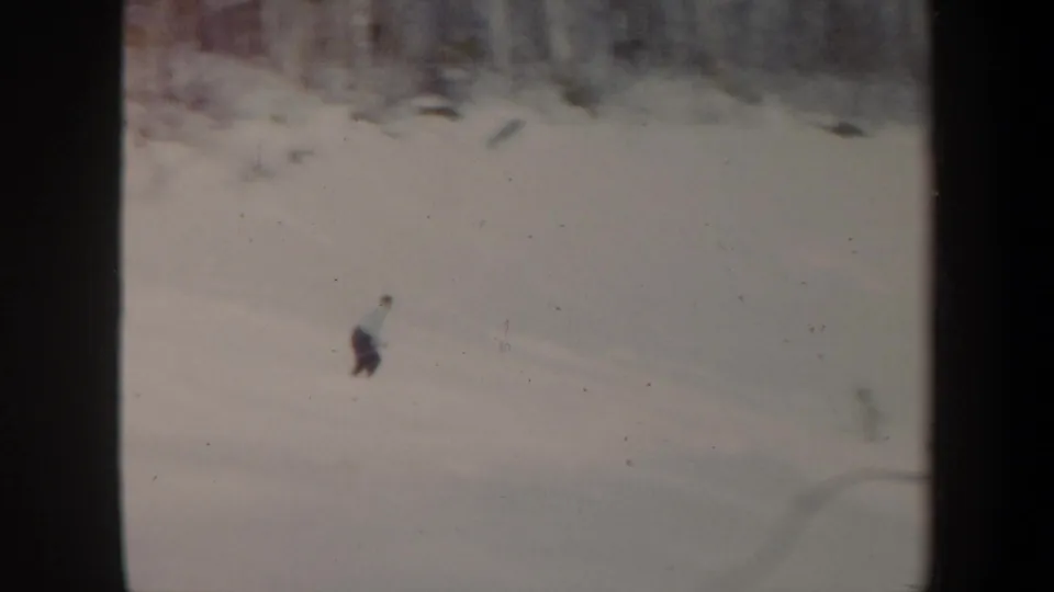 Distant 1962 Vermont 8mm view of a skier lower on a snowy hill, partly softened by film grain.