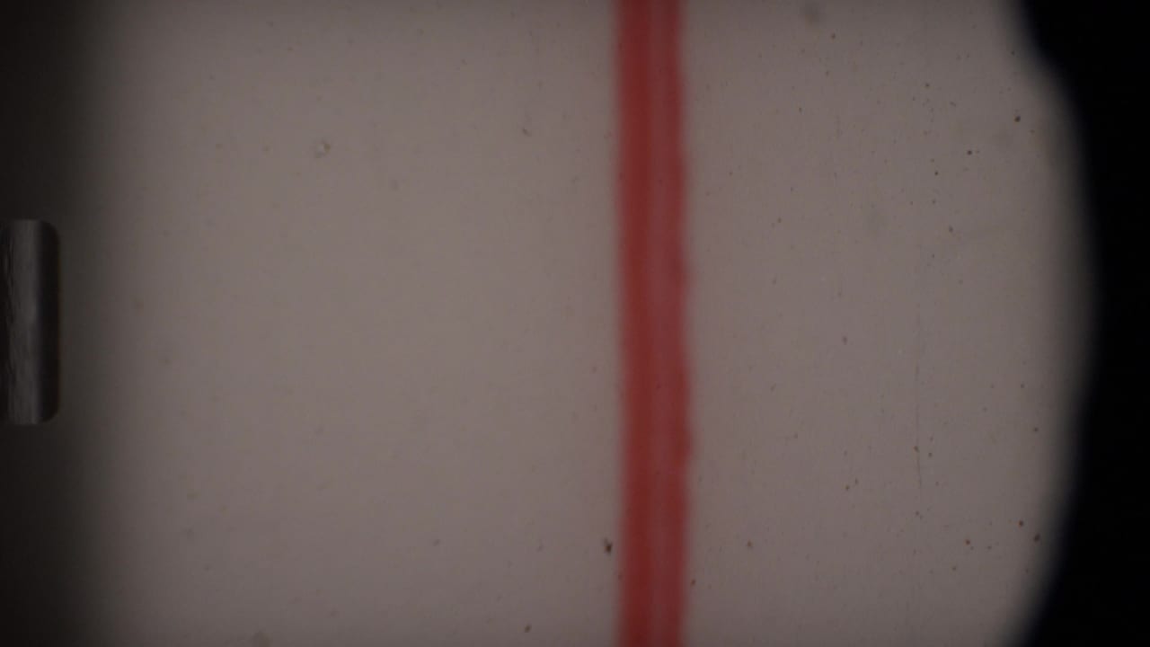 Close-up of the Angola 1969 8mm leader as the red handwritten line sits between dark rounded film-frame borders.