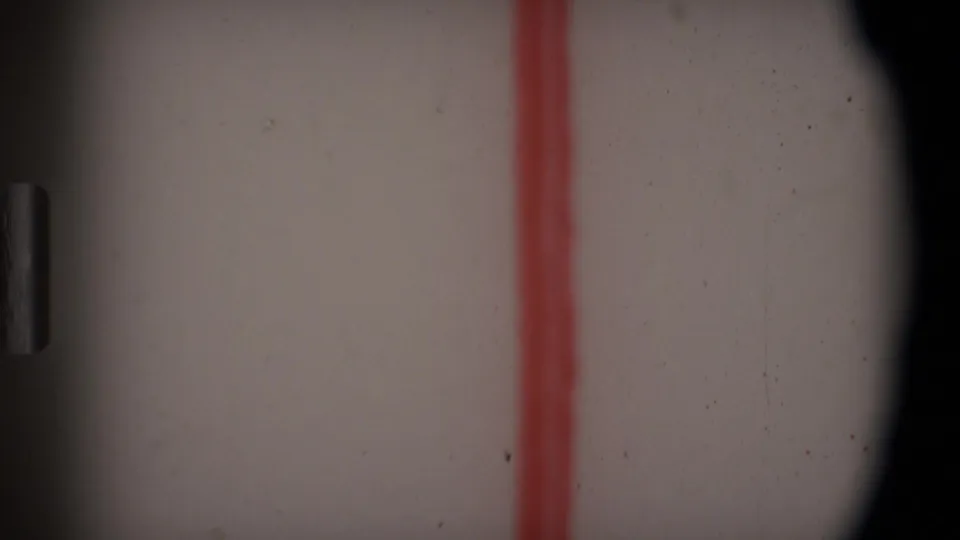 Close-up of the Angola 1969 8mm leader as the red handwritten line sits between dark rounded film-frame borders.