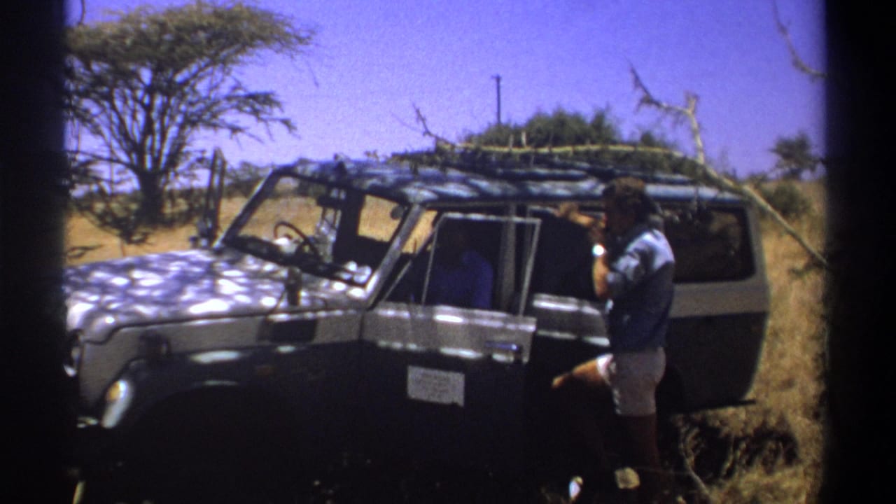 Man beside an open safari vehicle with another person visible inside.