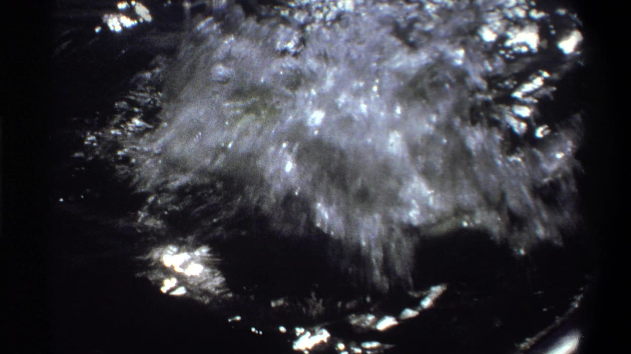 1969 Nigeria 8mm frame showing a fish breaking the water in a burst of spray beside a small boat.