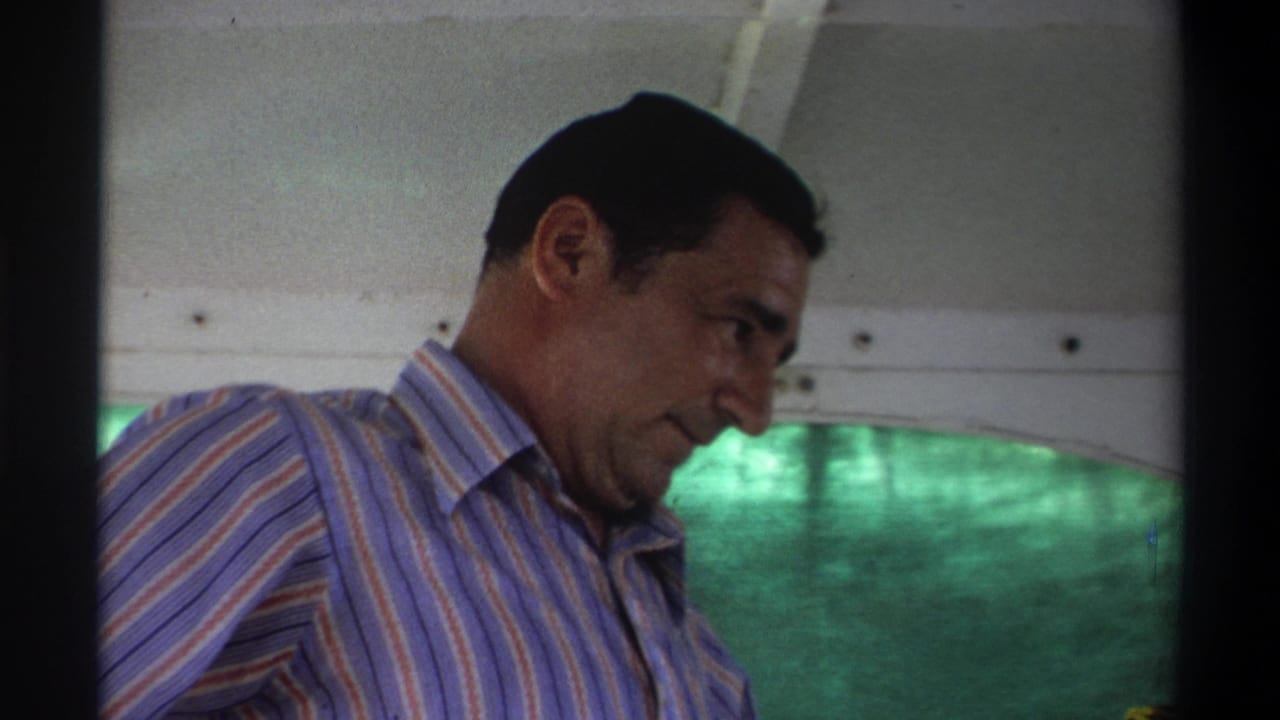 Man in a striped shirt leaning forward inside the boat, seen beside the window and canopy.