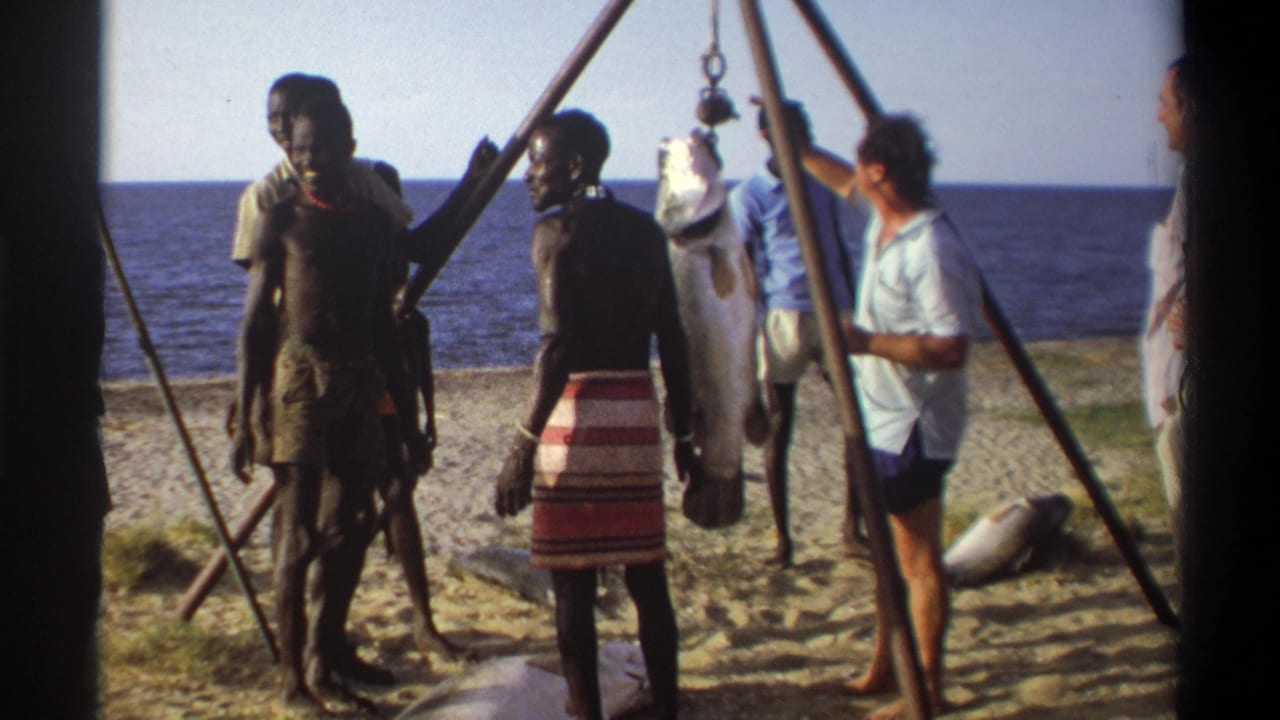 In the final 1969 Nigeria frame, men remain around the beach scale as the large fish hangs beside the sea.