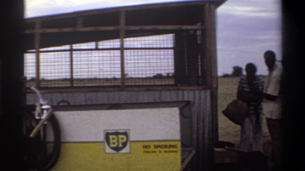 At the Nigerian airstrip, two men stand near the BP fuel station while the open field extends behind them.