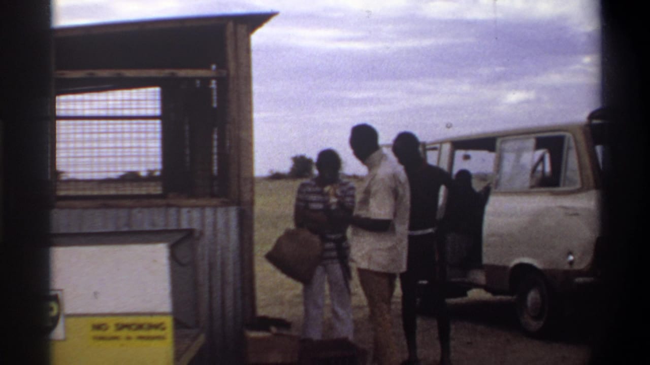 Several men stand with luggage beside a white and beige van near the BP fuel station in Nigeria in 1969.