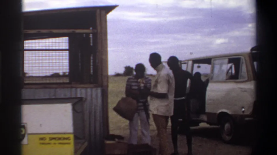 Several men stand with luggage beside a white and beige van near the BP fuel station in Nigeria in 1969.