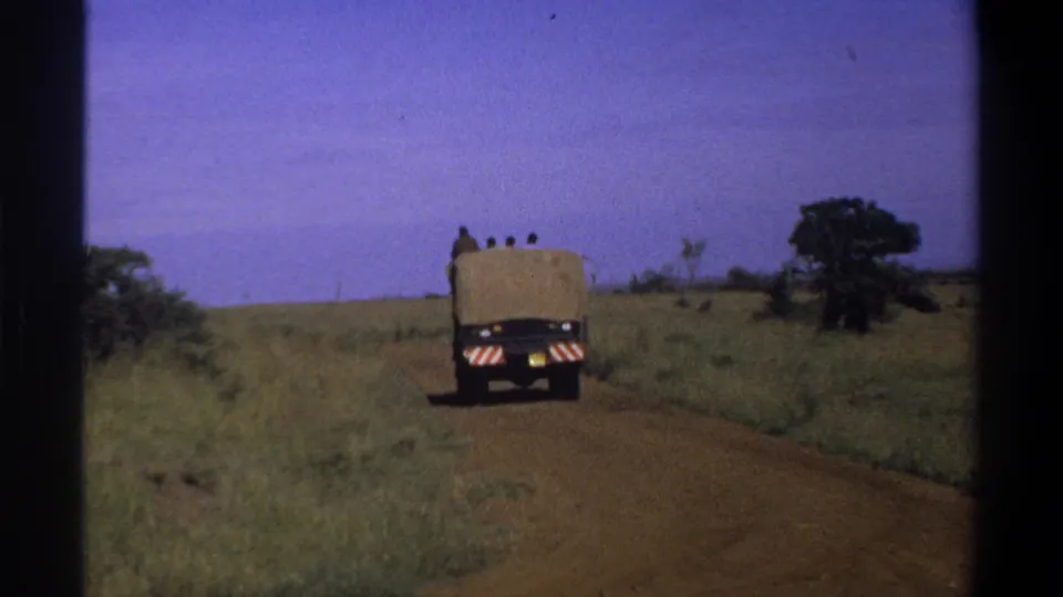 1969 Lagos, Nigeria 8mm frame with the rear of a canvas-covered truck small in the distance on a dirt road.