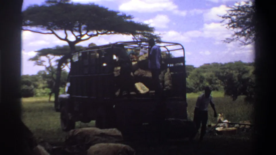 1969 Lagos 8mm frame with a worker walking near scattered cargo as another man remains on an open truck.