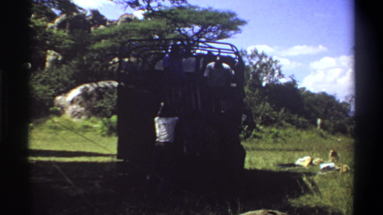 Handheld 8mm frame from Lagos in 1969 showing the stuck truck area with a man beside the vehicle in strong shadow.