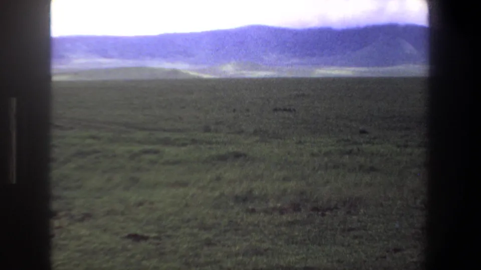 1969 Pretoria-area frame showing open grassland, distant mountain ridge, and a bright overcast sky through dark framing.