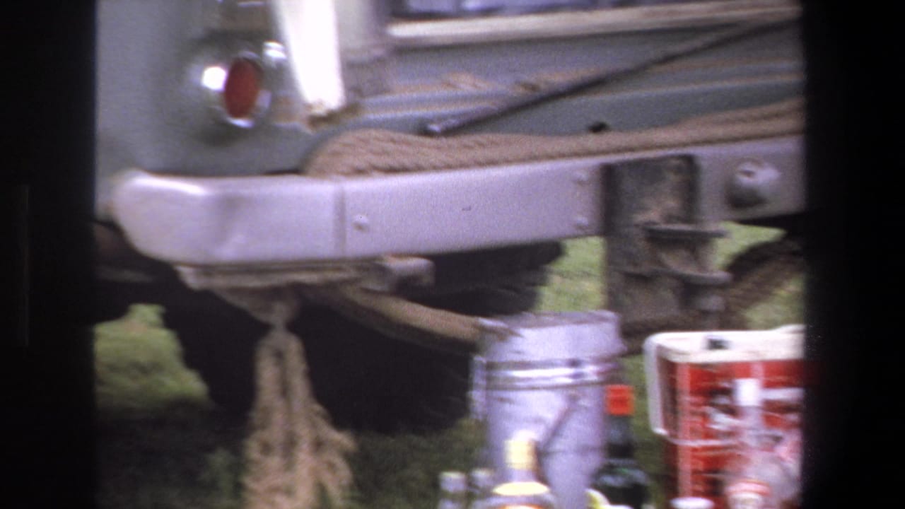 Rear of a truck with containers and bottles arranged on grass below the bumper.