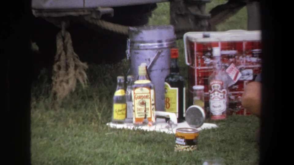A roadside arrangement of bottles, a metal bucket, a red cooler, and small supplies sits beside the truck in the 1969 Pretoria footage.