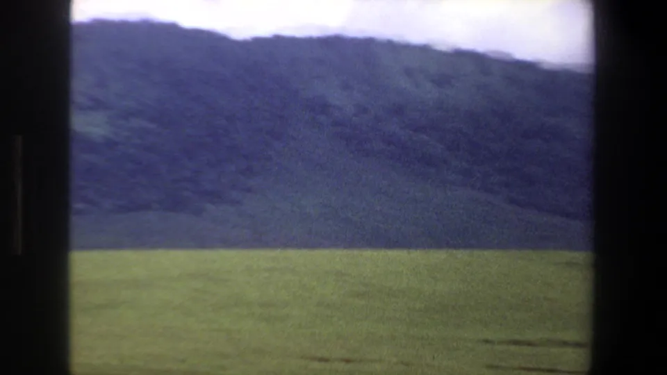 Pretoria 1969 landscape frame showing open grassland, a dark hillside, and overcast sky in 8mm color.