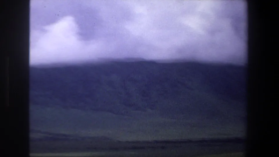 Pretoria-area landscape frame showing a dark ridgeline, low clouds, and green valley tones in soft 1969 8mm footage.