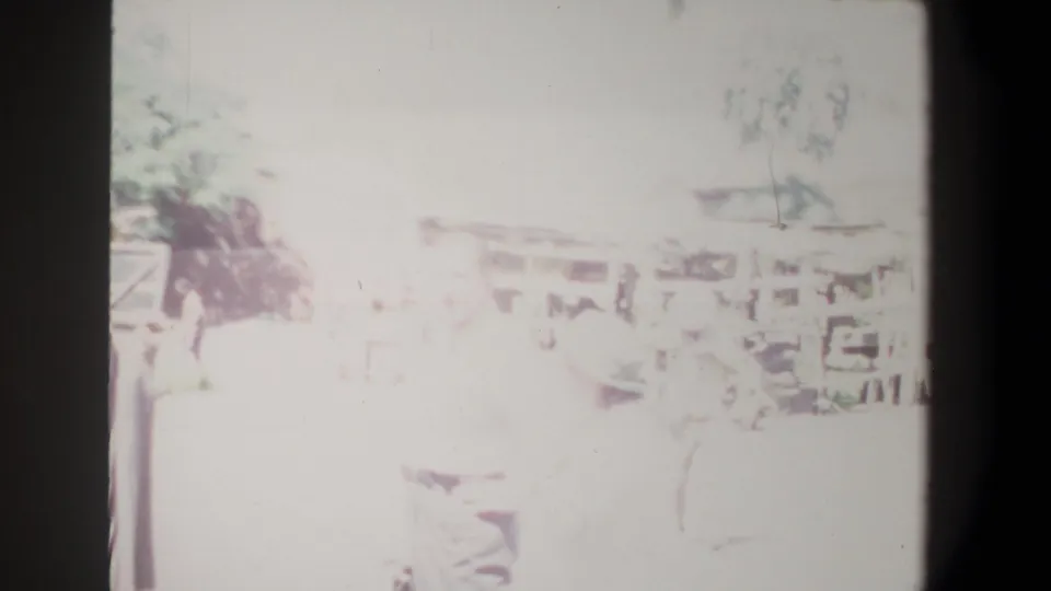 Final 1969 Pretoria frame with people moving near the open-bay structure, largely washed out by exposure and softened 8mm color.