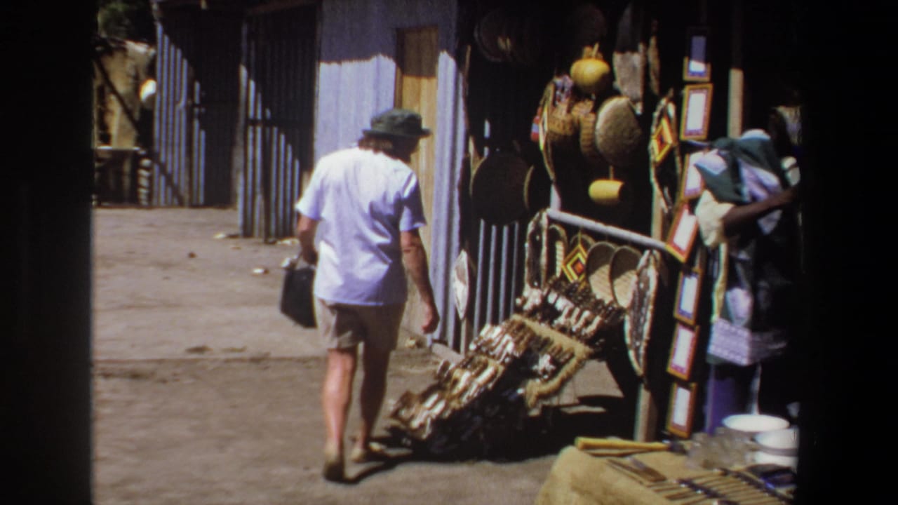 Tourist woman passes a vendor and craft display with baskets, hats, and textiles.