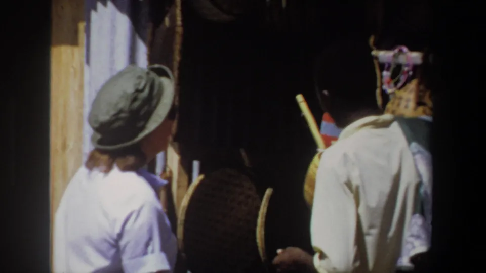 A closer handheld frame shows the woman and vendor from behind as they stand at the Pretoria craft stall with baskets in shadow.