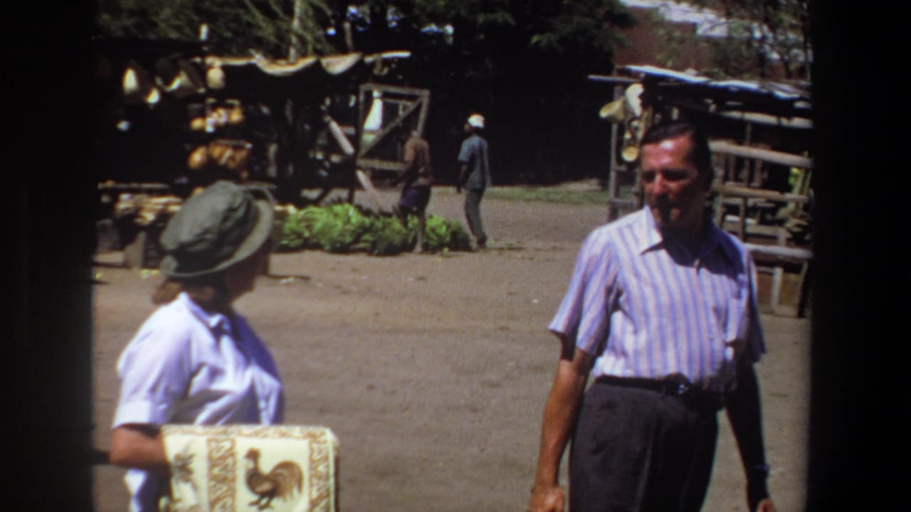 Man walking toward camera near a woman and market stalls.