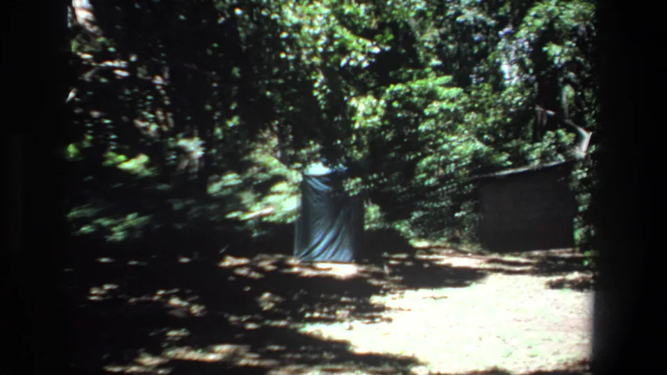 Wooded Pretoria-area outdoor view from the same 1969 8mm clip, showing trees, shade, and a small tent-like structure.