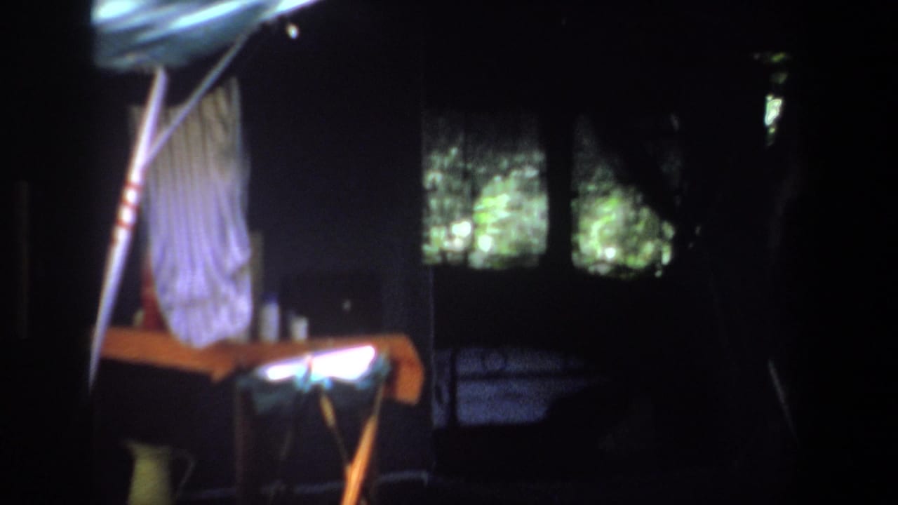 Opening 8mm frame from the Pretoria reel shows a dark shaded foreground with a partial chair-like object and bright trees outside.