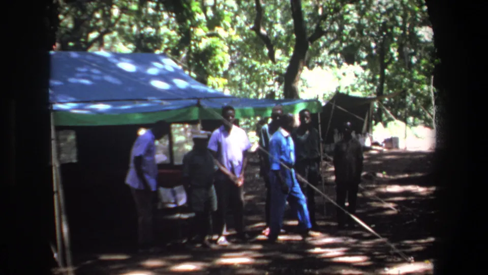 At the end of the 1969 Pretoria clip, men move beside the tent while others remain standing in the wooded clearing.