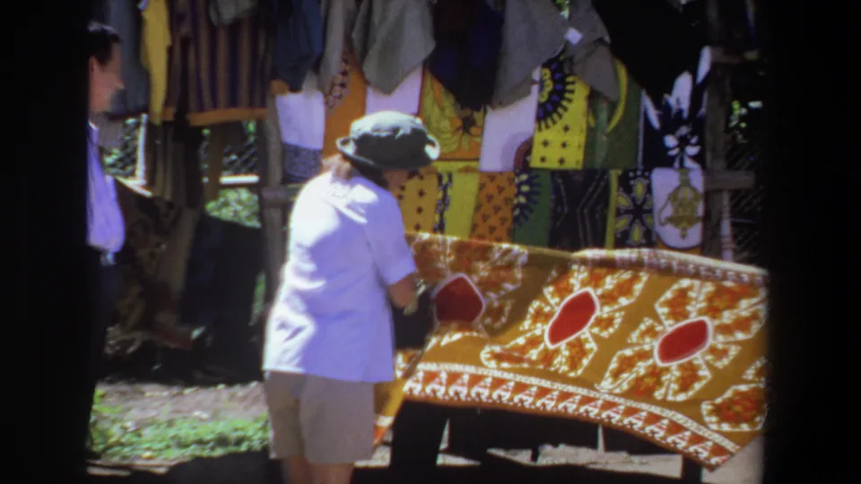 The final frame shows a closer 1969 Pretoria market view of the woman and vendor with the yellow textile filling much of the frame.