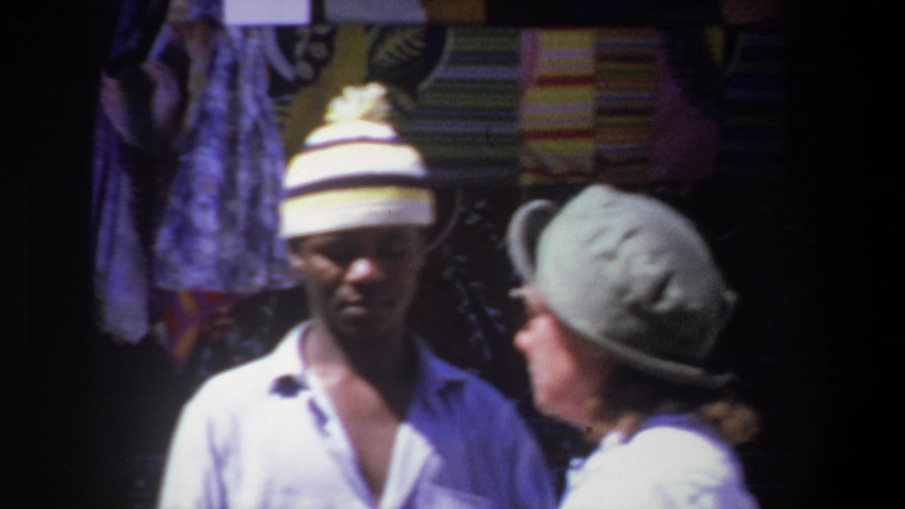 Man in a striped knit hat stands beside a woman in a wide-brimmed hat at a textile stall.
