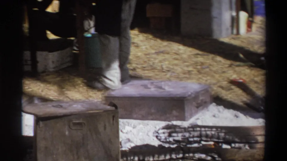 The lower view shows camp supplies, dirt ground, ash, and a large fire pit or cooking area in 1969 Cape Town footage.