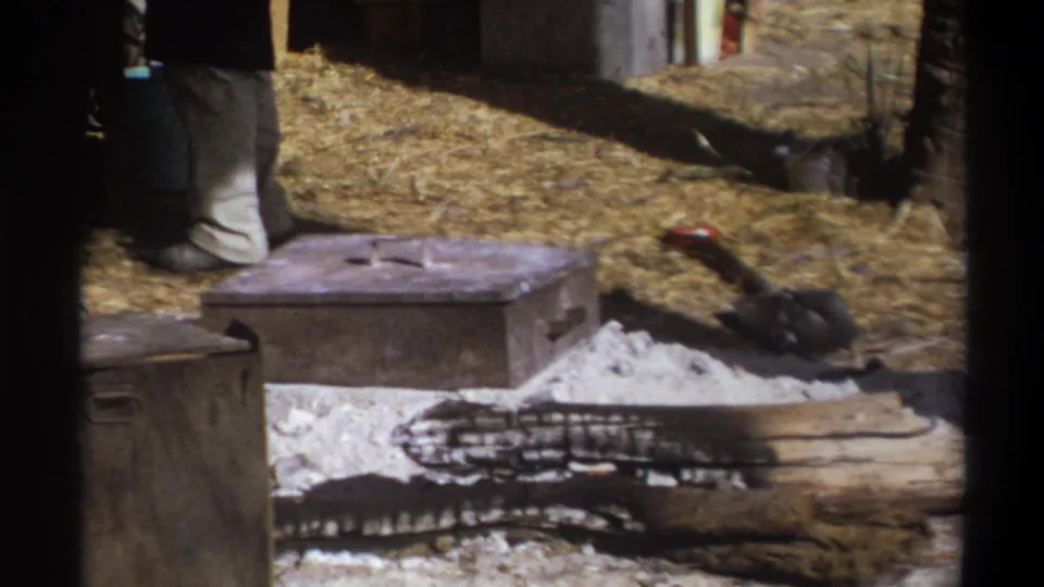 A 1969 Cape Town camp scene shows a partly visible man near crates, ash, and a large outdoor cooking or fire area.